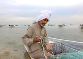 بحاران بحرينيان يشدان شباك الصيد قبل الدخول لصيد الأسماك في بحر المالكية
